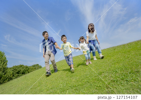 公園の丘で遊ぶ4人家族 公園の丘で遊ぶ4人家族 127154107