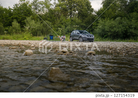 Camping by the River with SUV and Campfire 127154319