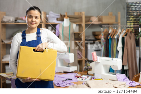 Woman sewing machine repairman standing in workshop Woman sewing machine repairman standing in workshop 127154494
