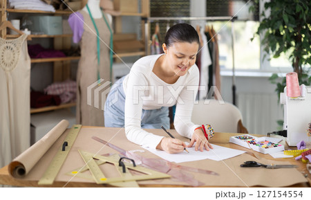 Asian woman drawing a sketch of clothes on paper 127154554