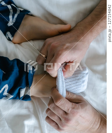 Dad slowly pulls down and pulls the white socks off the babys feet. High quality photo 127154842