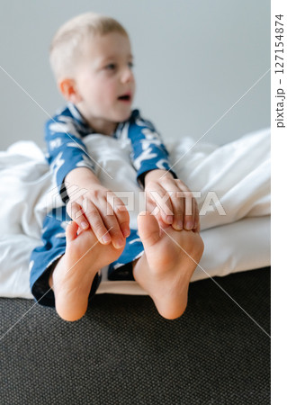 a little blond-haired boy in blue pajamas in his parents' bed lounging in the white sheets. High quality photo a little blond-haired boy in blue pajamas in his parents' bed lounging in the white sheets. High quality photo 127154874