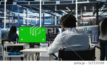 Data center worker with paraplegia using green screen PC to apply node tree programming. Server hub admin with disability uses visual programming on mockup computer to identify data patterns, camera A Data center worker with paraplegia using green screen PC to apply node tree programming. Server hub admin with disability uses visual programming on mockup computer to identify data patterns, camera A 127155594