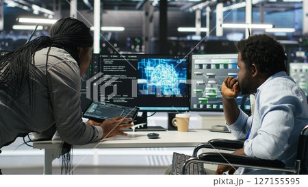 Admin in wheelchair and data center coworker working together using AI node tree software to minimize downtime. Server hub IT expert in disability and colleague using visual programming app, camera B Admin in wheelchair and data center coworker working together using AI node tree software to minimize downtime. Server hub IT expert in disability and colleague using visual programming app, camera B 127155595