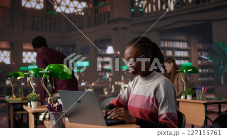 African american student consulting academic research collection at library, studying for upcoming exams to obtain her university diploma. Girl works on a scholarship, education. Camera B. African american student consulting academic research collection at library, studying for upcoming exams to obtain her university diploma. Girl works on a scholarship, education. Camera B. 127155761