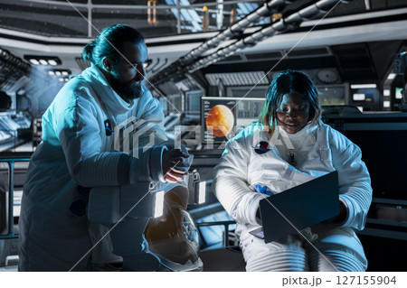 Teamworking astronauts use tablet to ensure safe operation during long distance space travel to Mars. Orbital station crew monitors system stability during cosmic journey to red planets Teamworking astronauts use tablet to ensure safe operation during long distance space travel to Mars. Orbital station crew monitors system stability during cosmic journey to red planets 127155904