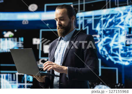 Entrepreneur uses laptop to review artificial intelligence brain system on dashboards, using high tech data visualization for coding, analytics and machine learning. Strategic development. Entrepreneur uses laptop to review artificial intelligence brain system on dashboards, using high tech data visualization for coding, analytics and machine learning. Strategic development. 127155968