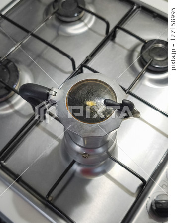 Moka pot rich espresso on stainless steel stovetop, traditional italian coffee ritual in rustic kitchen Moka pot rich espresso on stainless steel stovetop, traditional italian coffee ritual in rustic kitchen 127158995