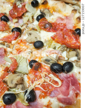 Close up of freshly baked pizza showcasing variety of toppings including olives, mushrooms, and meats, italian cuisine 127159007
