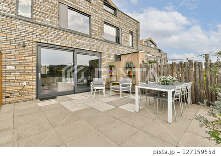 A stylish outdoor patio features modern furniture, a stone wall backdrop, and greenery, creating a perfect space for relaxation and social gatherings. 127159558
