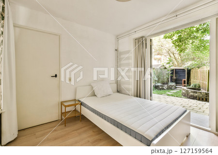 Bright and spacious bedroom featuring minimalistic furniture design, large windows with a view of nature, and a clean aesthetic for a serene atmosphere. Bright and spacious bedroom featuring minimalistic furniture design, large windows with a view of nature, and a clean aesthetic for a serene atmosphere. 127159564