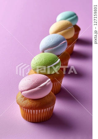 Mini cupcakes with pastel frosting arranged in a line on pink background create an appealing visual treat. Ideal for bakery, event planning, catering concepts that celebrate sweet occasions Mini cupcakes with pastel frosting arranged in a line on pink background create an appealing visual treat. Ideal for bakery, event planning, catering concepts that celebrate sweet occasions 127159801