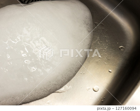 A piece of ice in a metal sink. 127160094