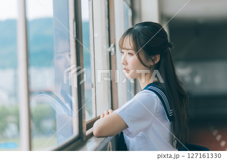 学校の廊下から外を眺める女子高生 127161330