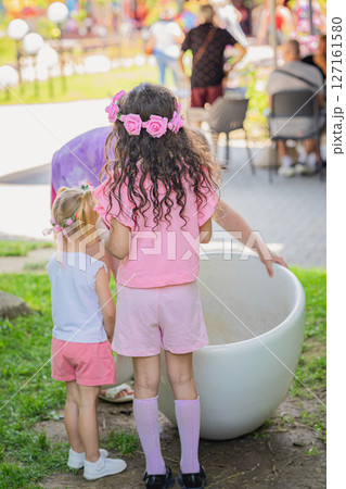 Girls wearing pink flower crowns and colorful outfits enjoying festival outdoors on sunny day. annual Kazanlak rosa damascene Festival. Concept of childhood joy, festive spirit 127161580