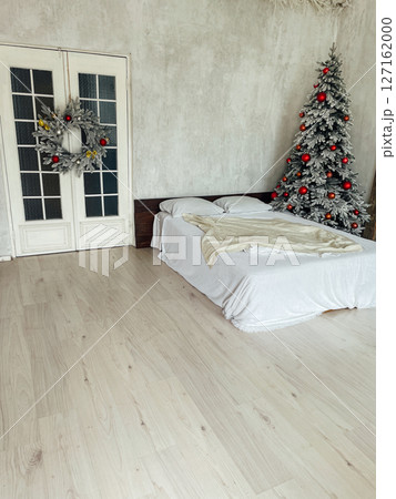 Bed in the bedroom with a Christmas tree and gifts 127162000