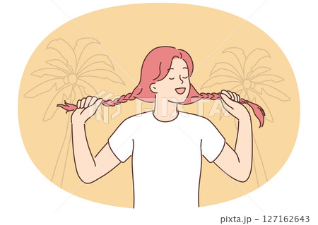 Young woman holding pigtails standing on beach with palm trees for metaphor for inner child 127162643