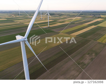 Aerial view of wind turbine on an agricultural filed at sunset. Close up of blades 127162898