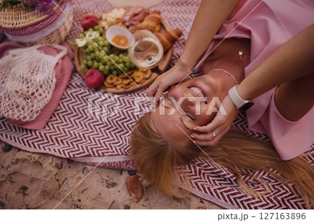 Beautiful young woman lying on picnic blanket smiling at camera 127163896