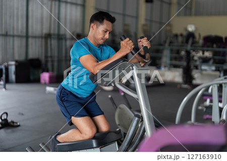 Fitness Focus. Man using elliptical machine for cardio workout. 127163910