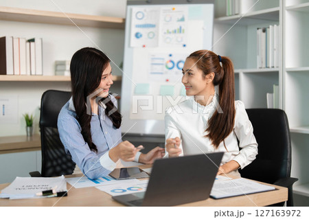 Empowered Women in Business. Two professionals collaborating on financial projects in an office. 127163972