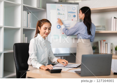 Women in Business. Female colleagues discussing data and strategies in a modern office. Women in Business. Female colleagues discussing data and strategies in a modern office. 127164001