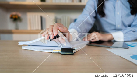 Office Organization. Close-up of a woman organizing documents with a binder in a modern workspace. Office Organization. Close-up of a woman organizing documents with a binder in a modern workspace. 127164002