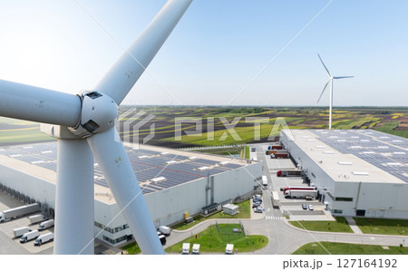 Wind turbine on a background of logistics centers with solar panels on roofs Wind turbine on a background of logistics centers with solar panels on roofs 127164192