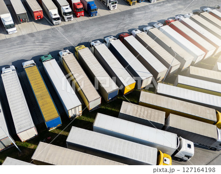 Aerial view of a large truck parking lot at a logistics hub, with multiple commercial semi trucks parked in organized rows 127164198