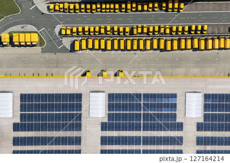 Delivery vans hub with solar panel on a roof. Fleet of yellow post vehicles Delivery vans hub with solar panel on a roof. Fleet of yellow post vehicles 127164214