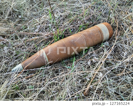 Explosive shell resting in grassland after a conflict, highlighting dangers of unexploded ordnance in rural areas Explosive shell resting in grassland after a conflict, highlighting dangers of unexploded ordnance in rural areas 127165224