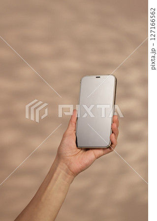 woman holding smartphone with blank screen on beige background, mockup woman holding smartphone with blank screen on beige background, mockup 127166562