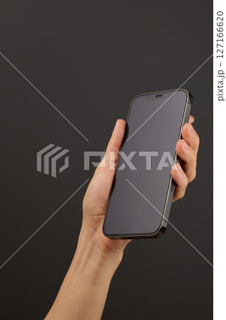woman holding smartphone with her left hand isolated on black background woman holding smartphone with her left hand isolated on black background 127166620