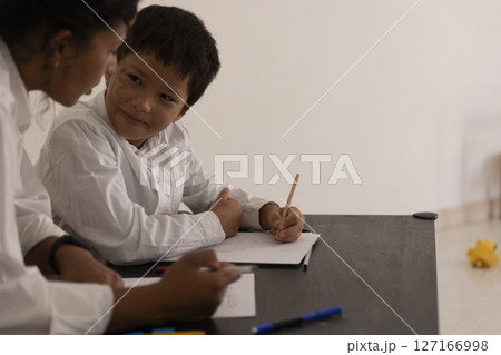Teacher helping young student drawing at desk Teacher helping young student drawing at desk 127166998