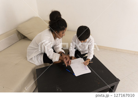 Mother helping son with homework, homeschooling on the couch Mother helping son with homework, homeschooling on the couch 127167010