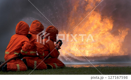 Firefighter Rescue team training in fire fighting extinguisher. Teamwork Firefighter fighting with flame using fire hose chemical water foam spray engine. Fireman teams wear hard hat safety uniform Firefighter Rescue team training in fire fighting extinguisher. Teamwork Firefighter fighting with flame using fire hose chemical water foam spray engine. Fireman teams wear hard hat safety uniform 127167598