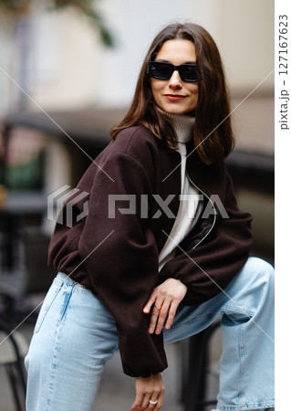 Fashionable woman wearing sunglasses and posing in urban setting 127167623