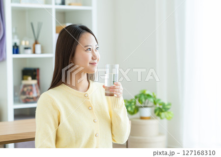 自宅でミネラルウォーターを飲む若い女性 自宅でミネラルウォーターを飲む若い女性 127168310