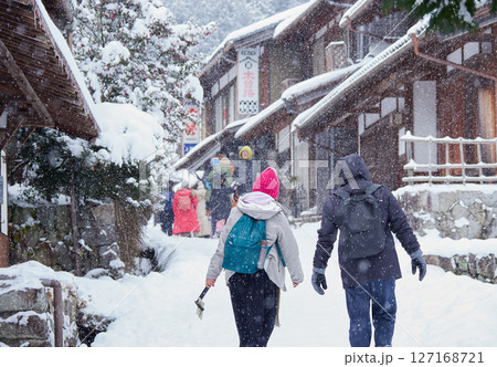 冬の中山道の観光名所馬籠宿の古い町並みの雪景色と観光客の姿 127168721