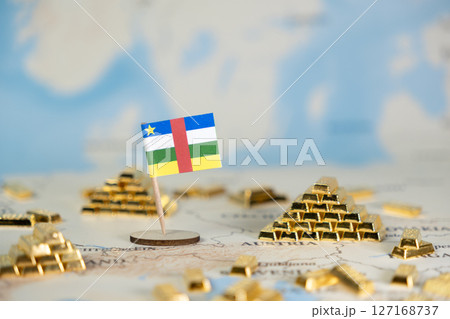 Central African Republic flag standing beside gleaming gold bar piles on a world map, representing national economic resources, investment, and wealth management, with copy space Central African Republic flag standing beside gleaming gold bar piles on a world map, representing national economic resources, investment, and wealth management, with copy space 127168737