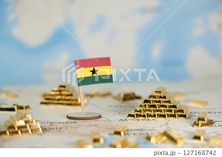 Ghanaian flag standing amidst glittering gold bars on a world map, reflecting the nation's rich natural resources and economic potential with ample copy space 127168742