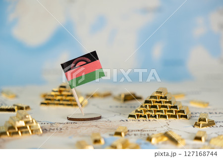 Malawi flag stands amidst numerous shiny gold bars on a blurred world map, symbolizing national wealth, resources, and global investment 127168744