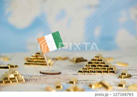 Ivorian flag with miniature gold bars on map symbolizing Ivory Coast's mineral wealth, gold export industry, and foreign investment potential 127168765