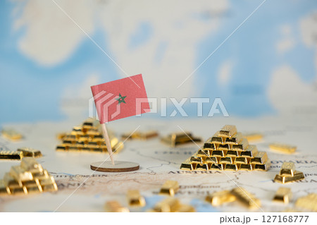 Moroccan flag stands among gold bars on a world map, symbolizing national economic power, wealth, global trade, and financial prosperity with ample copy space 127168777