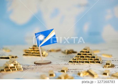 Marshall Islands flag stands among gleaming gold bars on a world map, symbolizing national wealth, economic strength, and global investment with copy space 127168783
