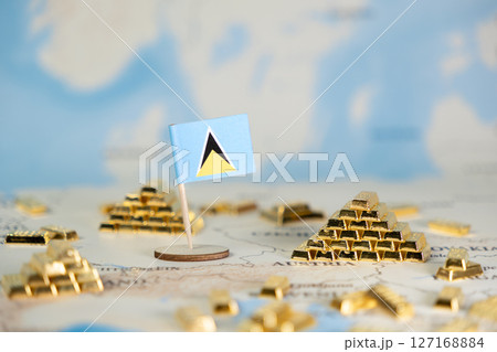 Saint Lucia flag stands on a map with gold bar piles, symbolizing national economic prosperity, global finance, valuable resources, and copy space Saint Lucia flag stands on a map with gold bar piles, symbolizing national economic prosperity, global finance, valuable resources, and copy space 127168884