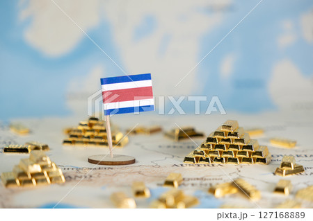 Costa Rica flag near golden bullion bars on a map, representing national wealth, economic growth, global finance, and investment opportunities, offering copy space 127168889