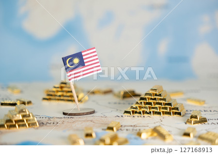 Malaysian flag prominently stands with shiny gold bars scattered across a world map, symbolizing national wealth, economic strength, and global finance, offering ample copy space Malaysian flag prominently stands with shiny gold bars scattered across a world map, symbolizing national wealth, economic strength, and global finance, offering ample copy space 127168913