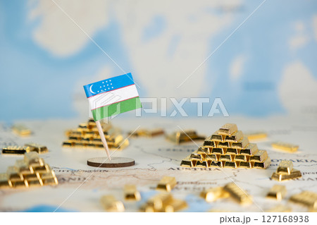 Uzbekistan flag with gold bars on a global map, depicting the nation's economic strength, strategic resources, and international financial standing with copy space 127168938
