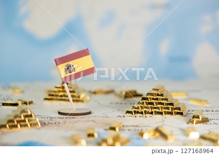 Spanish flag displayed with numerous gold bars on a world map, representing national economic strength, global finance, and investment, with copy space 127168964